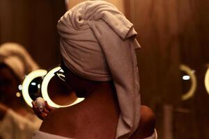 A woman gracefully applies nourishing moisturizer to her shoulder after a relaxing bath, embodying a radiant and rejuvenated skincare routine photo