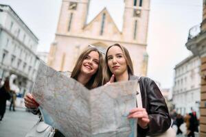 Two female tourists engage in lively discussion, surrounded by their luggage, as they plan their sightseeing journey through the bustling city streets, map in hand. photo