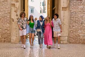 A diverse group of tourists, dressed in summer attire, strolls through the tourist city with wide smiles, enjoying their sightseeing adventure photo