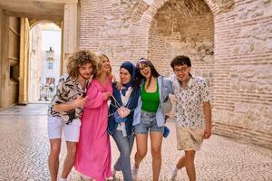 A diverse group of tourists, dressed in summer attire, strolls through the tourist city with wide smiles, enjoying their sightseeing adventure photo