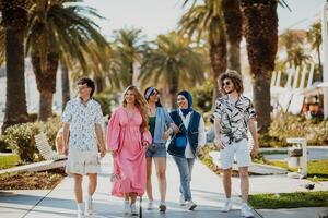 A diverse group of tourists, dressed in summer attire, strolls through the tourist city with wide smiles, enjoying their sightseeing adventure photo