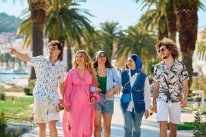 A diverse group of tourists, dressed in summer attire, strolls through the tourist city with wide smiles, enjoying their sightseeing adventure photo
