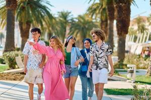 A diverse group of tourists, dressed in summer attire, strolls through the tourist city with wide smiles, enjoying their sightseeing adventure photo