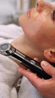 A woman massages her face using a gadget with microcurrents. video