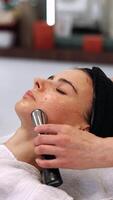 A woman massages her face using a gadget with microcurrents. video