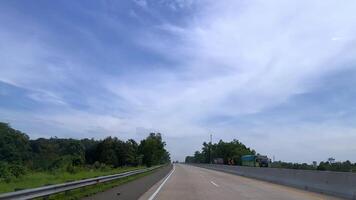 A highway with a blue sky and trees in the background. There are several carson the road video