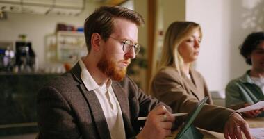 Portrait Of Red Bearded Businessman Working With Tablet And His Colleagues Discussing Project video