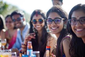 A group of people are smiling and sitting around a table with drinks and food photo
