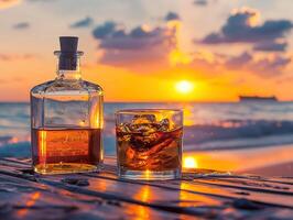 A bottle of liquor and a glass of liquor on a table by the ocean photo