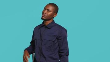 Security guard doing thinking hand gesture during surveillance shift, ensuring protection of property and personnel. Portrait of pensive man in uniform rubbing chin, studio background, camera A video
