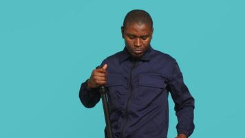 Portrait of security guard overseeing premises, turning on flashlight and preparing baton to detain suspects. Private law enforcement worker using lantern and truncheon gear, studio backdrop, camera A video