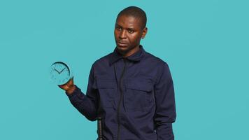 säkerhet vakt innehav klocka, rusa människor ut av fast egendom. porträtt av akter livvakt som visar besökare tid är godkänd, framställning för stängning ner plats, studio bakgrund, kamera en video