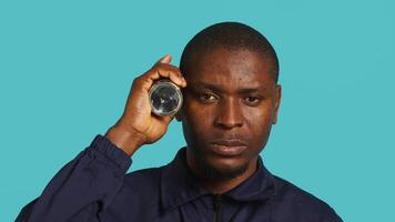 Headshot portrait of security employee tasked with evicting trespassers, turning on flashlight. Close up shot of patrolling agent using lantern, spotting intruders, studio background, camera A video