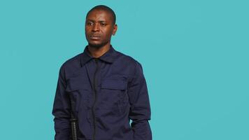 Portrait of security guard overseeing premises to prevent unwanted intrusion waving hand towards visitors. Private law enforcement worker doing greeting gesturing, studio backdrop, camera A video