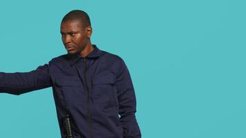 Security guard pointing finger at people to prevent them from gaining access in restricted areas. Portrait of stern bodyguard scolding and telling off unwanted visitors, studio background, camera A video