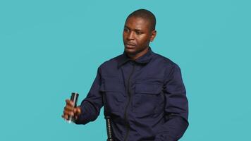 Security guard preventing criminal activity turning on flashlight after detecting trespasser. Portrait of bodyguard using lantern to spot criminals, calling over intruder, studio background, camera A video