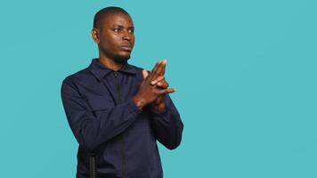 Security guard doing pretending to shoot gun hand gesture while being tasked with preventing criminal activity. Portrait of bodyguard doing pistol fingers gesturing, studio background, camera A video