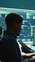 Vertical Governmental hackers analyzing data for cyber threat detection, looking at a big screen in high tech office. Highlight cyber intelligence, online security and prevention of digital threats. Camera B. video