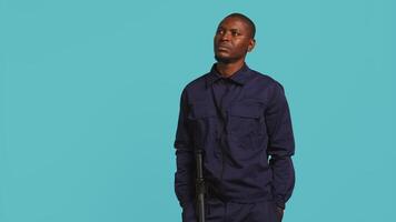 Security guard doing thinking hand gesture during surveillance shift, ensuring protection of property and personnel. Portrait of pensive man in uniform rubbing chin, studio background, camera B video