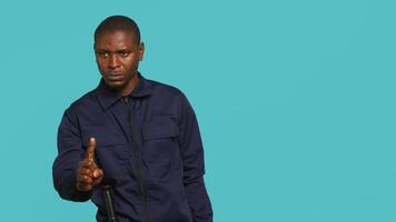 Portrait of security guard doing no gesturing with finger, prohibiting access while overseeing premises. Private law enforcement worker barring people from entering place, studio backdrop, camera A video