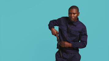 Security guard turning on flashlight and preparing baton to detect and detain suspects. Portrait of bodyguard using lantern and truncheon to subdue criminals, studio background, camera B video