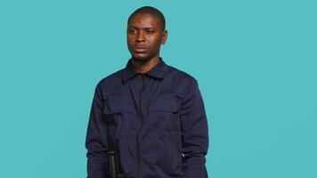 Portrait of smiling security agent securing assigned post, isolated against studio background. African american guardian prepared to handle security breaches and diffuse tense situations, camera A video