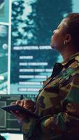 Vertical Woman high tech specialist studying satellite CCTV visualization on a big screen, preparing troops with insight for a new national safety mission. Female first lieutenant in command post. Camera A. video