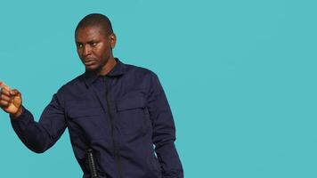porträtt av säkerhet ombud pekande finger på människor, varning dem medan säkring tilldelad posta, studio bakgrund. afrikansk amerikan väktare utskällning inkräktare, hantering säkerhet överträdelser, kamera en video