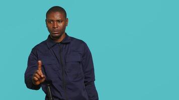 Security guard doing no gesturing with finger, prohibiting public access in restricted area. Portrait of stern bodyguard barring people from entering place, studio background, camera A video