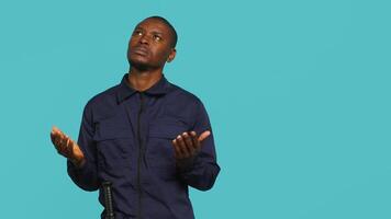 Security guard tasked with restricting unwanted access looking to sky, praying. Portrait of bodyguard waiting for miracle, doing spreading arms gesture, studio background, camera A video
