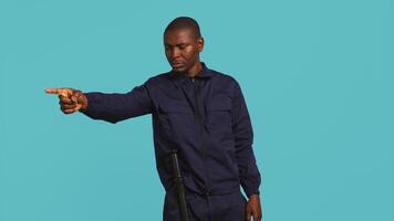 Security guard pointing finger at people to prevent them from gaining access in restricted areas. Portrait of stern bodyguard scolding and telling off unwanted visitors, studio background, camera B video