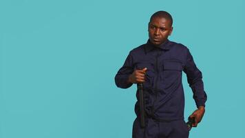 Portrait of security guard overseeing premises, turning on flashlight and preparing baton to detain suspects. Private law enforcement worker using lantern and truncheon gear, studio backdrop, camera B video
