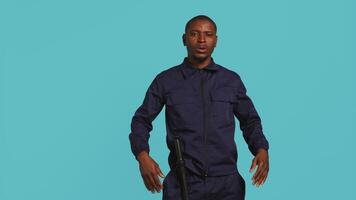 Portrait of security agent doing crowd control, securing assigned post, studio background. African american guardian pushing back unwanted trespassers, handling security breaches, camera B video