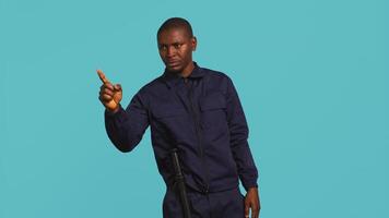 porträtt av säkerhet ombud pekande finger på människor, varning dem medan säkring tilldelad posta, studio bakgrund. afrikansk amerikan väktare utskällning inkräktare, hantering säkerhet överträdelser, kamera b video