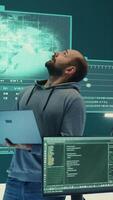 Vertical Cyber defense expert examining data on a big screen in governmental agency, focusing on cyber operations and digital security. Hacker ensures protection against cybercriminal activities. Camera B. video
