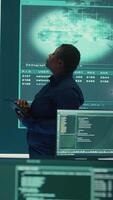 Vertical Professional IT expert working in a governmental security operations center, analyzing data on a big screen. Highlighting the importance of cyber security monitoring and threat analysis. Camera B. video