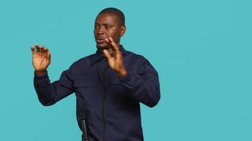 Portrait of security agent doing crowd control, securing assigned post, studio background. African american guardian pushing back unwanted trespassers, handling security breaches, camera A video