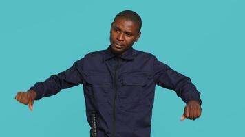Security guard doing thumbs down sign gesturing, denying public access in restricted area. Portrait of bodyguard doing negative hand gesture, being dismissive, studio background, camera A video