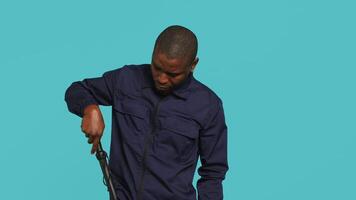 Portrait of security guard removing cane from belt while overseeing premises. Private law enforcement worker pointing to truncheon, threatening to subdue criminals, studio backdrop, camera A video