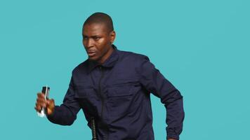 Portrait of security guard catching intruder with flashlight while overseeing premises. Private law enforcement worker calls over trespasser after detecting him with lantern, studio backdrop, camera A video