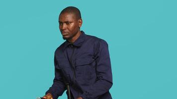 Portrait of security agent securing assigned post, turning on flashlight, studio background. African american guardian prepared to handle security breaches, using lantern device, camera A video