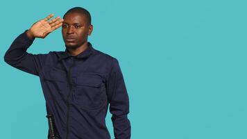 Security guard doing salute hand gesture, preparing to start job of deterring criminals. Portrait of bodyguard doing greeting gesturing and military pose, studio background, camera A video
