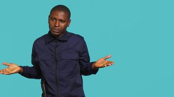 Clueless security guard shrugging shoulders, unable to answer people inquiries. Portrait of bodyguard doing lacking knowledge hand gesture, isolated over studio background, camera A video