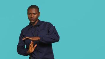 Security guard doing time out sign gesturing, being tasked with ceasing unwanted access. Portrait of stern bodyguard showing pause hand gesture, doing interrupting gesture, studio background, camera A video
