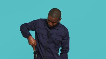 porträtt av säkerhet ombud avlägsnande batong från bälte, använder sig av den till säkra tilldelad posta, studio bakgrund. afrikansk amerikan väktare pekande finger till batong, hantering säkerhet överträdelser, kamera en video