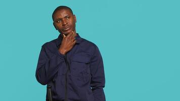 Security guard doing thinking hand gesture, being tasked with preventing criminal activity and detaining suspects. Portrait of pensive bodyguard rubbing chin, studio background, camera A video