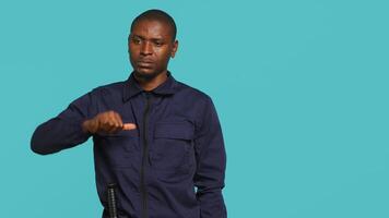 Portrait of security agent doing thumbs down sign gesturing, refusing entry while securing assigned post, studio background. Guardian doing negative hand gesture, handling security breaches, camera A video