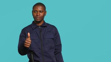 Lycklig säkerhet vakt håller på med tummen upp tecken gestikulerar med finger, förebyggande offentlig tillgång i begränsad område. porträtt av leende livvakt håller på med positiv hand gest, studio bakgrund, kamera en video
