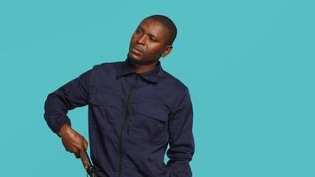 Portrait of security guard scratching head with baton while overseeing premises, thinking. Pensive private law enforcement worker daydreaming, rubbing chin, studio backdrop, camera A video