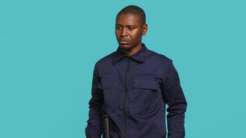 Portrait of security guard overseeing premises to prevent intrusion turning on flashlight to detect suspects. Private law enforcement worker using lantern device, studio backdrop, camera A video